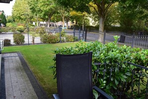 Een verzorgde tuin met een geplaveid pad, een metalen hek en verschillende struiken.