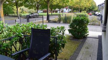 A garden area with a paved walkway, a metal fence, and a bench.