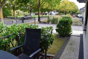 Ein Gartenbereich mit einem gepflasterten Weg, einem Metallzaun und einer Bank.
