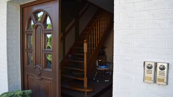 A wooden door with a glass panel, a staircase with wooden railings, and a white brick wall.