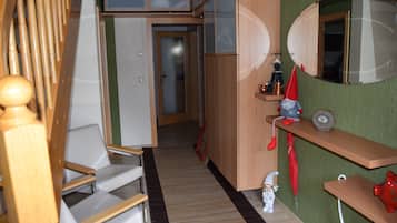 A narrow hallway with a wooden chair, a small table, and a red toy figure.