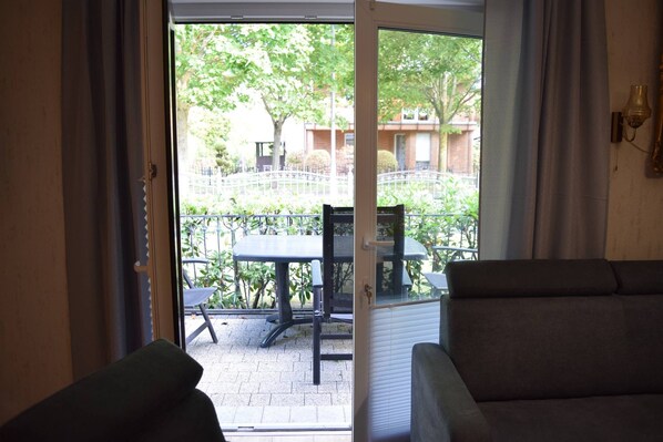 Eine geöffnete Schiebetür, die zu einer Terrasse mit Tisch und Stühlen führt.