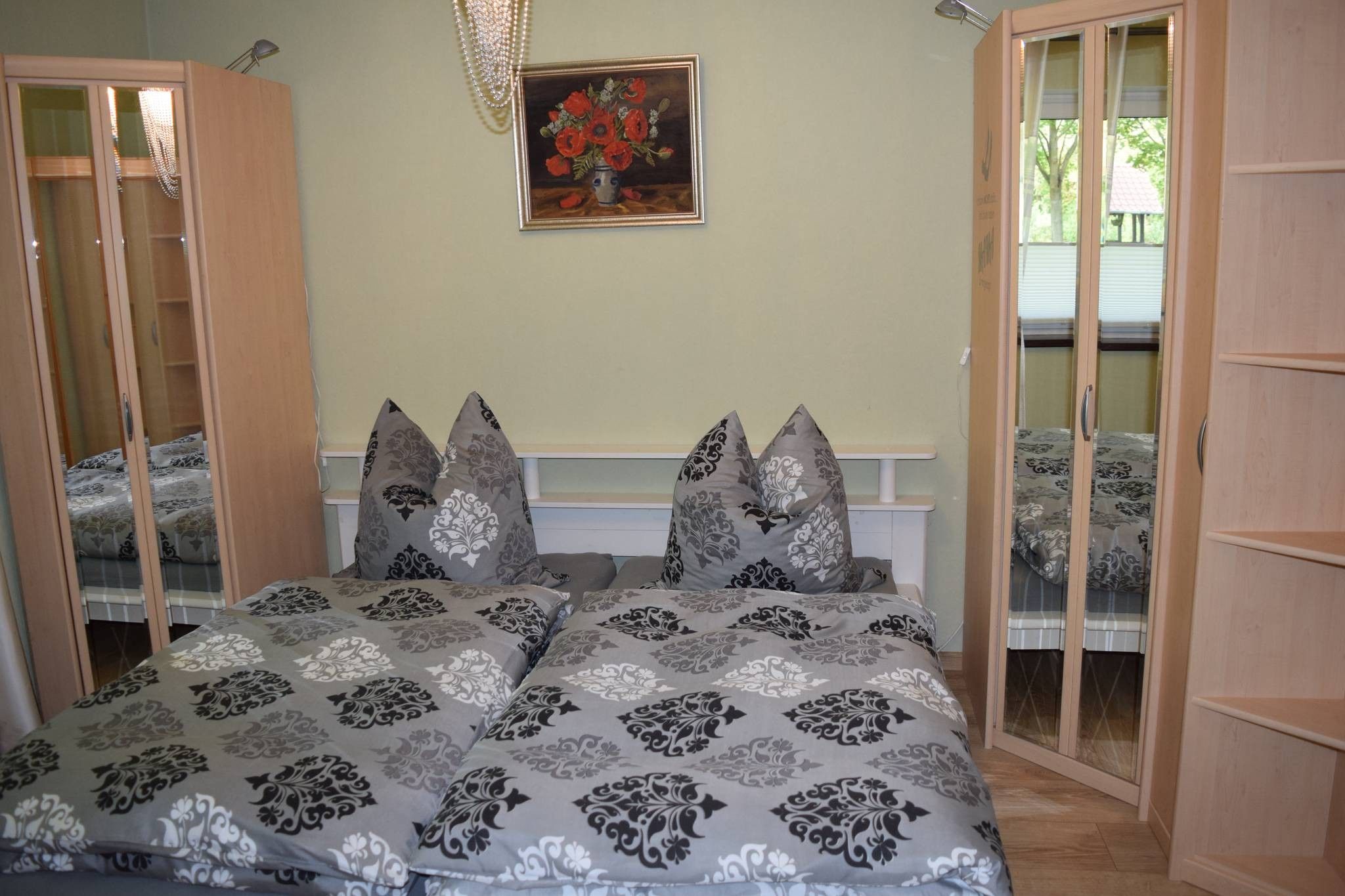 Een slaapkamer met een bed, twee nachtkastjes, een schilderij en een raam.