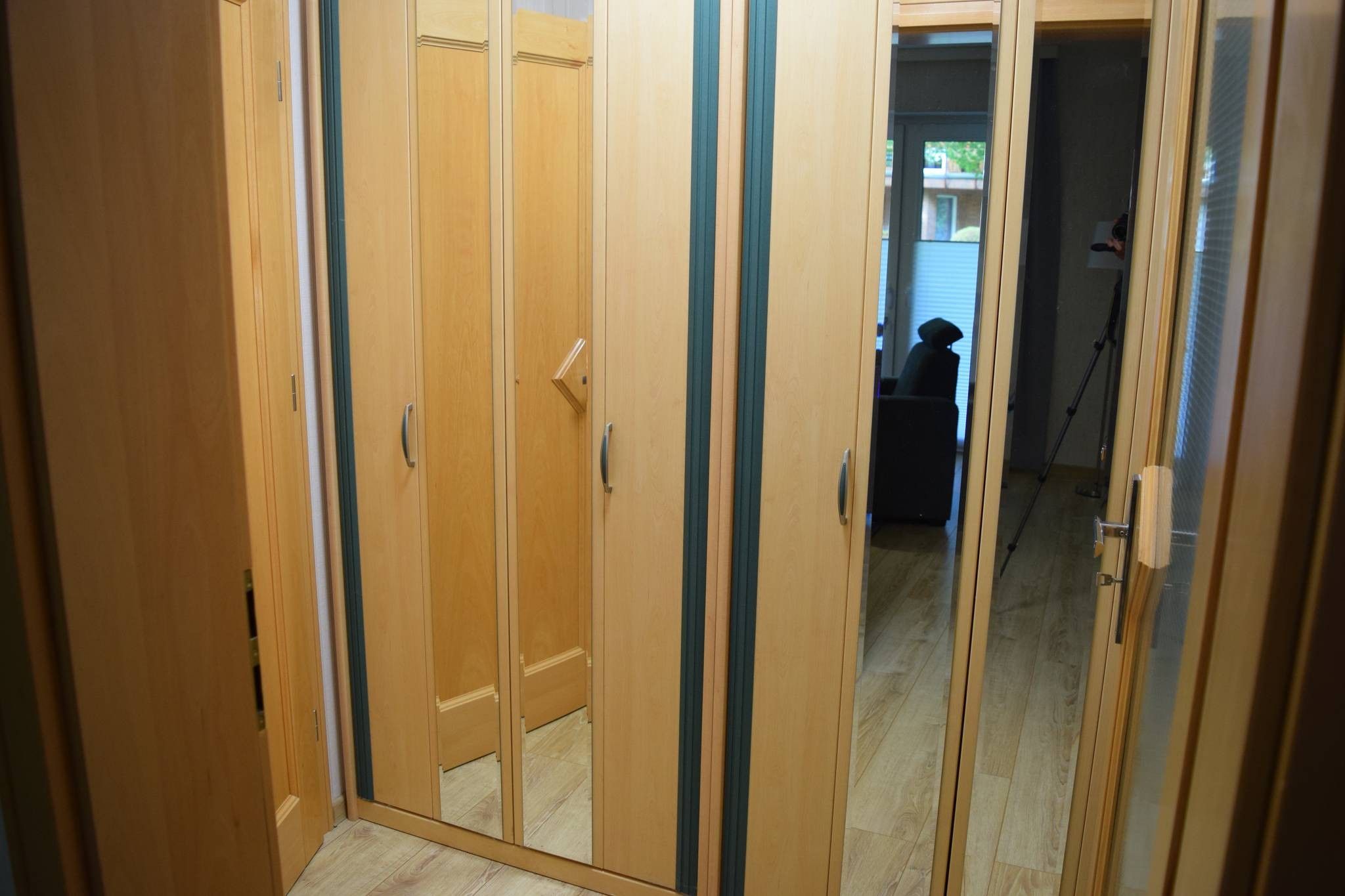 Un pasillo con puertas de madera y vistas a una habitación con una silla y una mesa.
