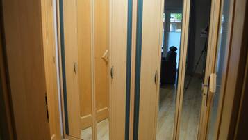 Un pasillo con puertas de madera y vistas a una habitación con una silla y una mesa.
