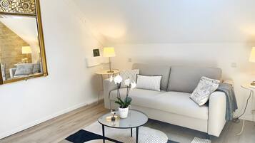 A modern living room with a sofa, coffee table, lamps, and a decorative mirror.