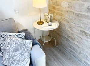 Una habitación acogedora con un sofá, una pequeña mesa redonda con una lámpara y un objeto decorativo sobre la mesa.