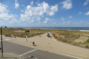 A coastal road with a pedestrian path, a flag, and a clear sky. - Holiday apartment with 1 bedroom (Katwijk aan Zee)