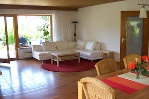 Ein Wohnzimmer mit einer Couch, einem Couchtisch und einem Esstisch mit Stühlen.