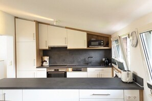 A modern kitchen with white cabinets, a black countertop, and a microwave. - Holiday apartment with 1 bedroom (Titisee-Neustadt)