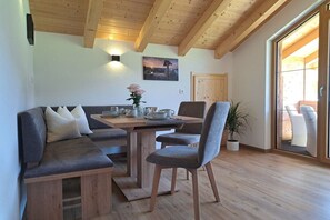 A cozy dining area with a wooden table, grey upholstered seating, and a potted plant. - Holiday apartment with 1 bedroom (Schönau am Königssee)