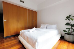 Ein Hotelzimmer mit einem großen Bett, einem Holzschrank und einer Zimmerpflanze.