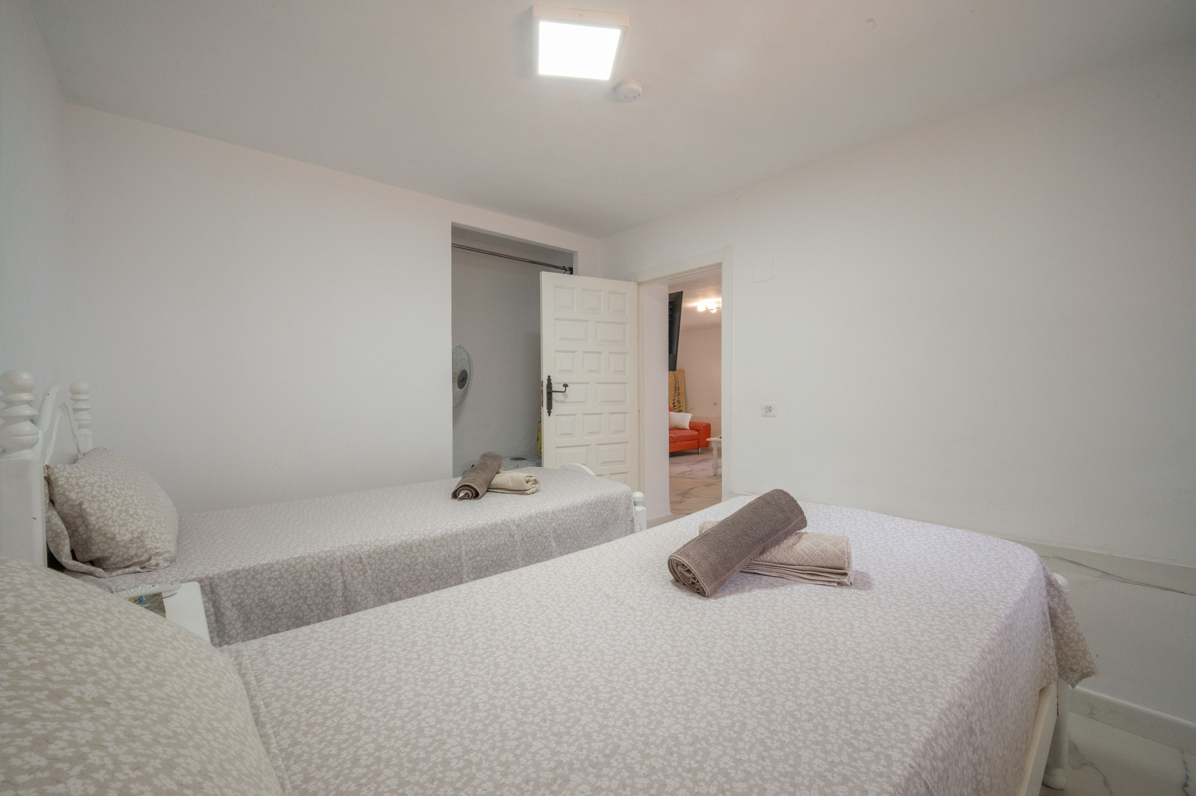 Un dormitorio con dos camas individuales, una puerta blanca y una mesita con una toalla.
