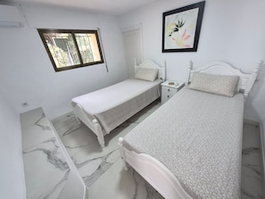 A bedroom with two single beds, a bedside table with a lamp, a window, and a framed picture on the wall. - Apartment 'Inferior' with Balcony, Wi-Fi and Air Conditioning (Calpe)
