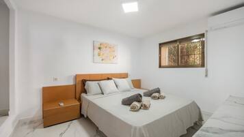 Een slaapkamer met een bed, een nachtkastje, een kunstwerk aan de muur, een raam met tralies en een marmeren vloer.