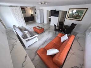 Una sala de estar con sofá, reposapiés y un comedor con sillas.