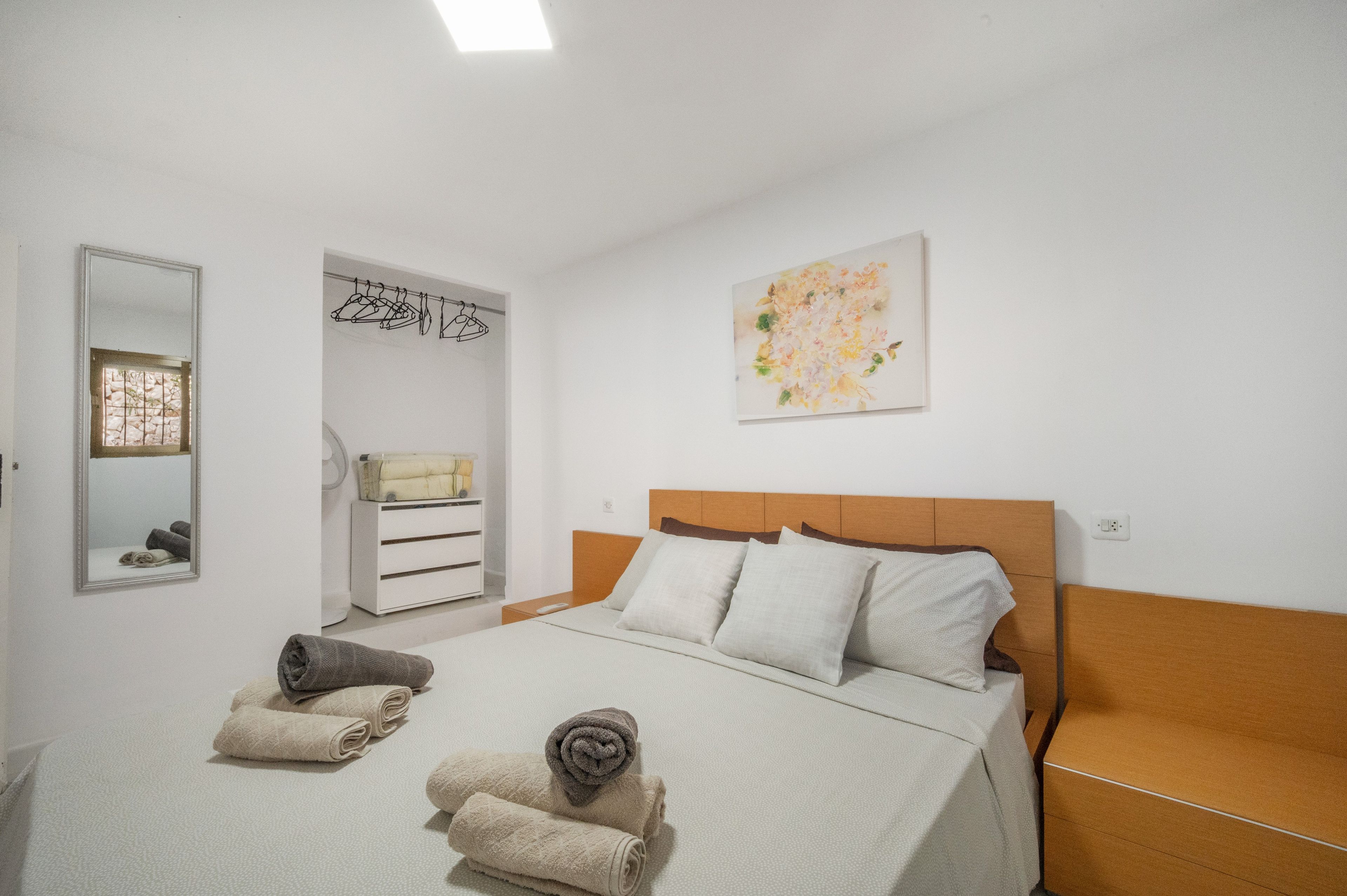 Een hotelkamer met een bed, een dressoir, een spiegel en een schilderij aan de muur.