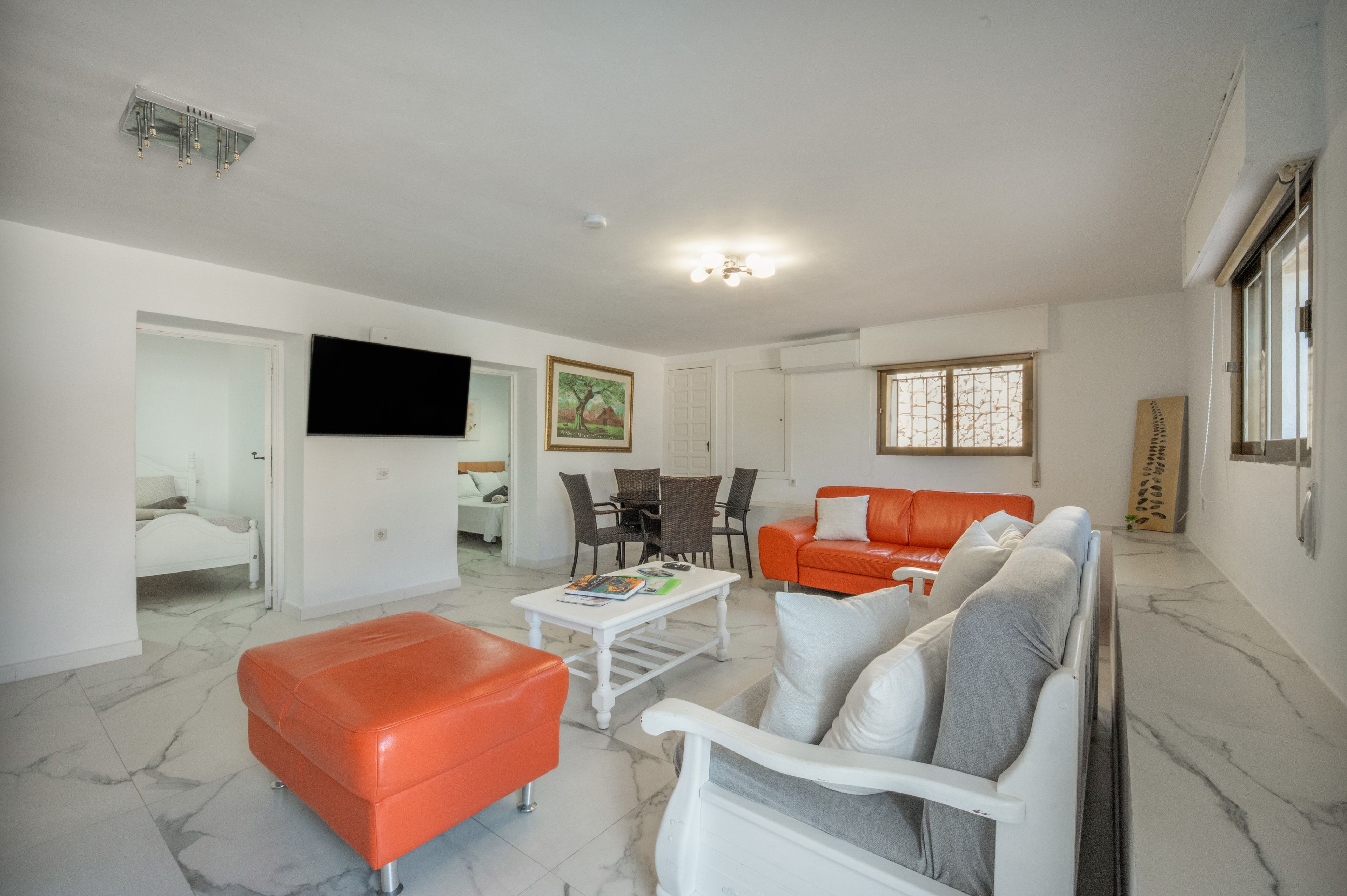 A living room with a sofa, ottoman, coffee table, and a television.