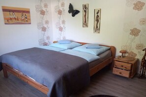 A bedroom with a bed, a nightstand, and wall decorations including a butterfly and framed pictures. - Haus Hoffmann Apartment A (Zell-Mosel)