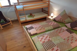 A bunk bed with a quilted mattress, a small bedside table with a lamp, and a chair with a cushion. - "Grünten" in the Seeblick house (Niedersonthofen)