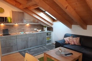 A compact kitchen with a skylight, a black sofa, and a wooden coffee table. - "Grünten" in the Seeblick house (Niedersonthofen)