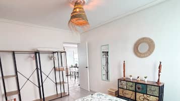 A bedroom with a bed, a dresser, a mirror, and a hanging light fixture.