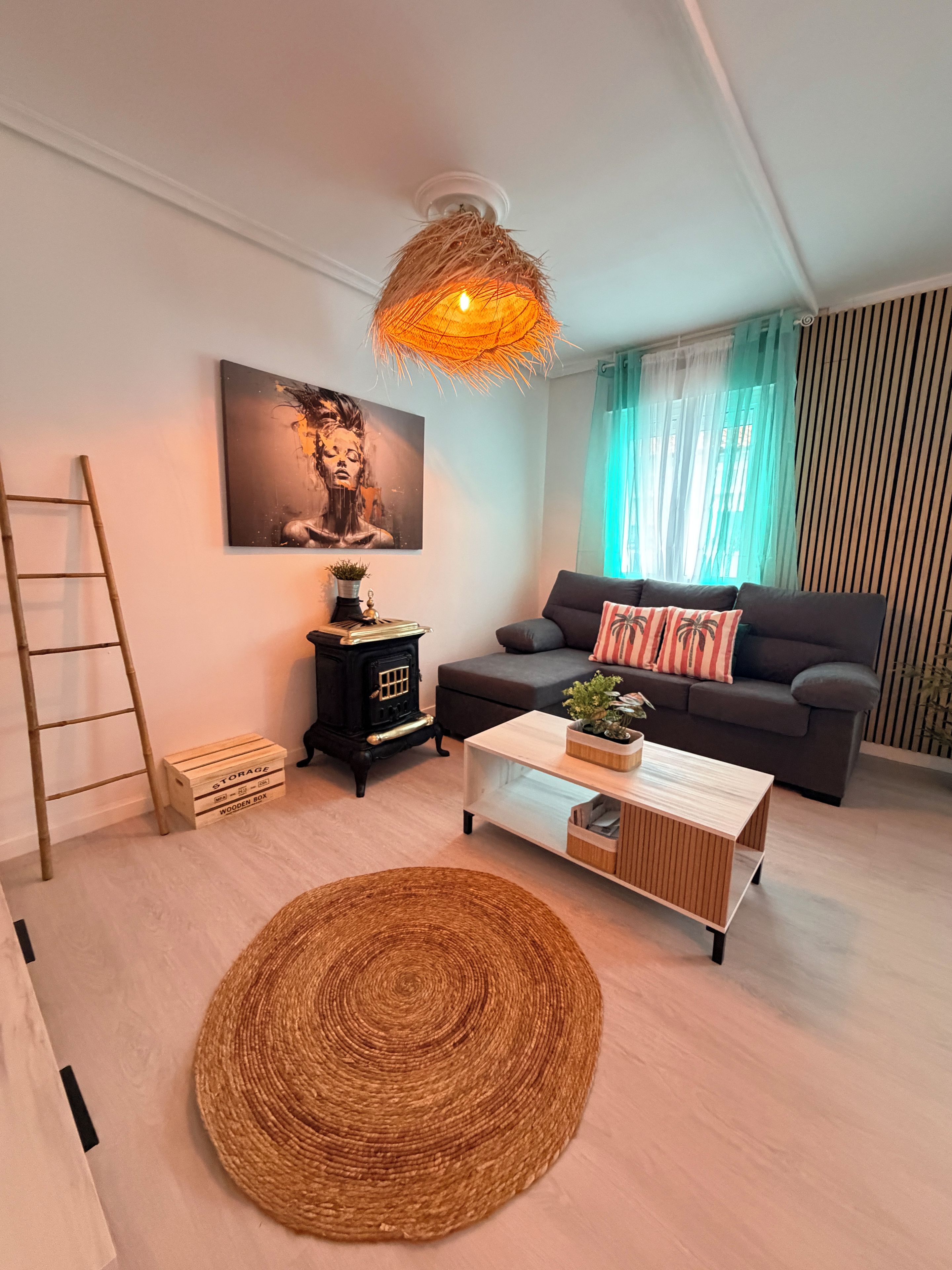 A modern living room with a sofa, a wooden coffee table, a woven rug, a decorative lamp, and a painting on the wall.