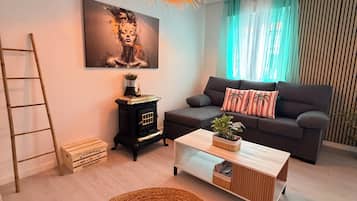 A modern living room with a sofa, a wooden coffee table, a woven rug, a decorative lamp, and a painting on the wall.