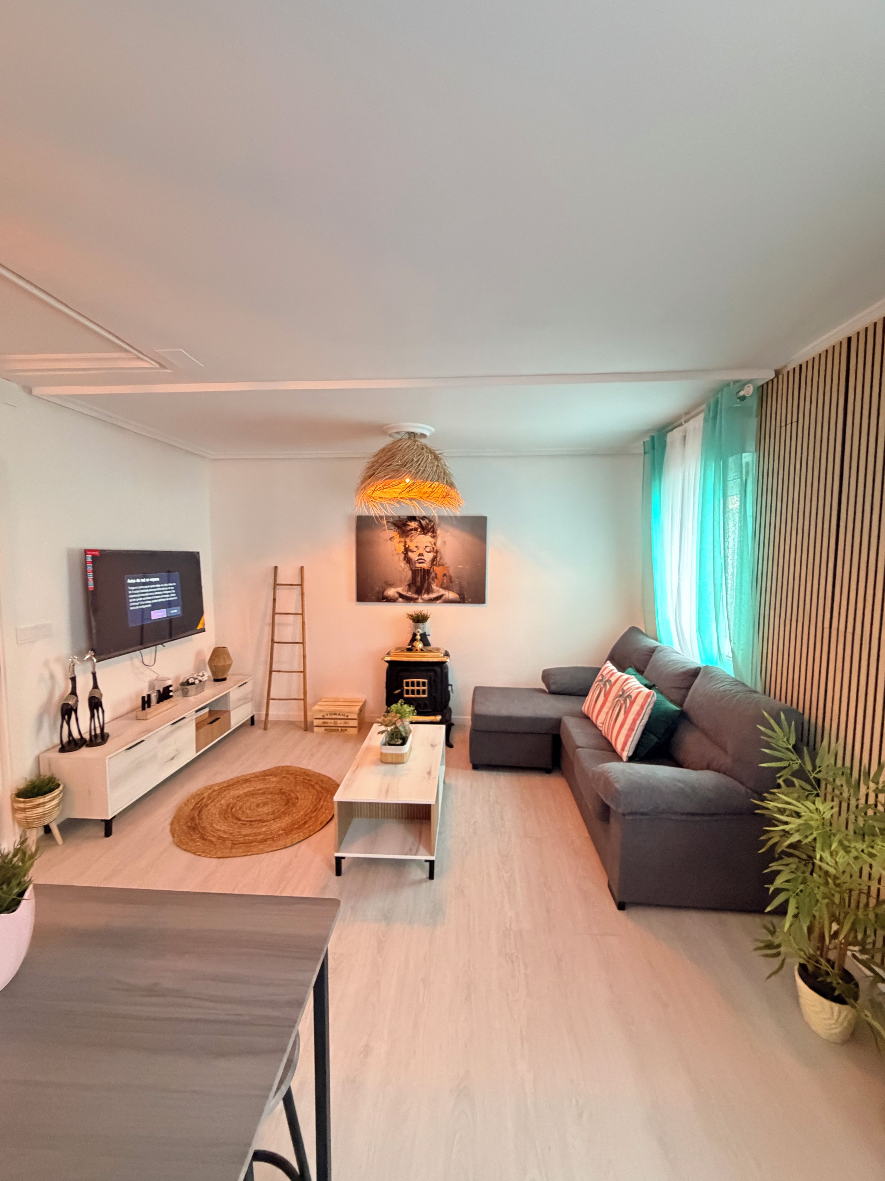 Una sala de estar moderna con un televisor de pantalla plana, un sofá, una mesa de centro y una lámpara decorativa.