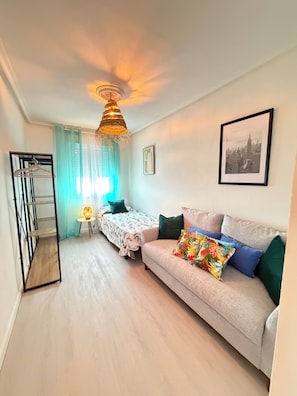 A cozy living room with a sofa, a bed, a hanging light fixture, and a framed picture on the wall. - Itos Flats, Cudillero (La Atalaya)
