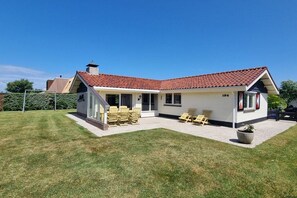 Ein zweistöckiges Haus mit Ziegeldach, einer überdachten Terrasse mit Gartenmöbeln und der Hausnummer 194.