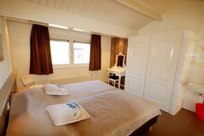 Een hotelkamer met een bed, een bureau, een stoel, een spiegel en een kledingkast.