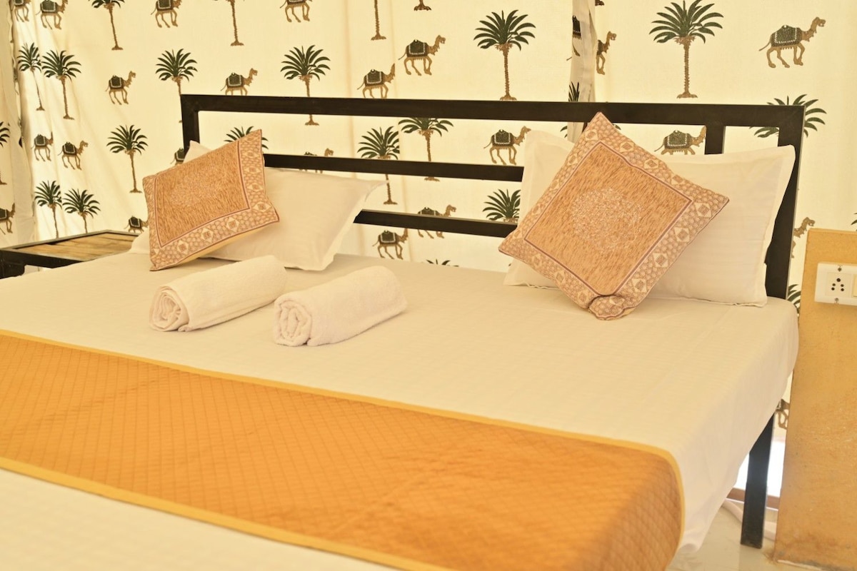 Un letto rifatto con due cuscini e due asciugamani arrotolati, una testiera in legno e una parete decorata.