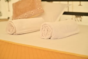 A neatly made bed with rolled white towels and a wooden headboard. - Desert Walk Camp (Jaisalmer)