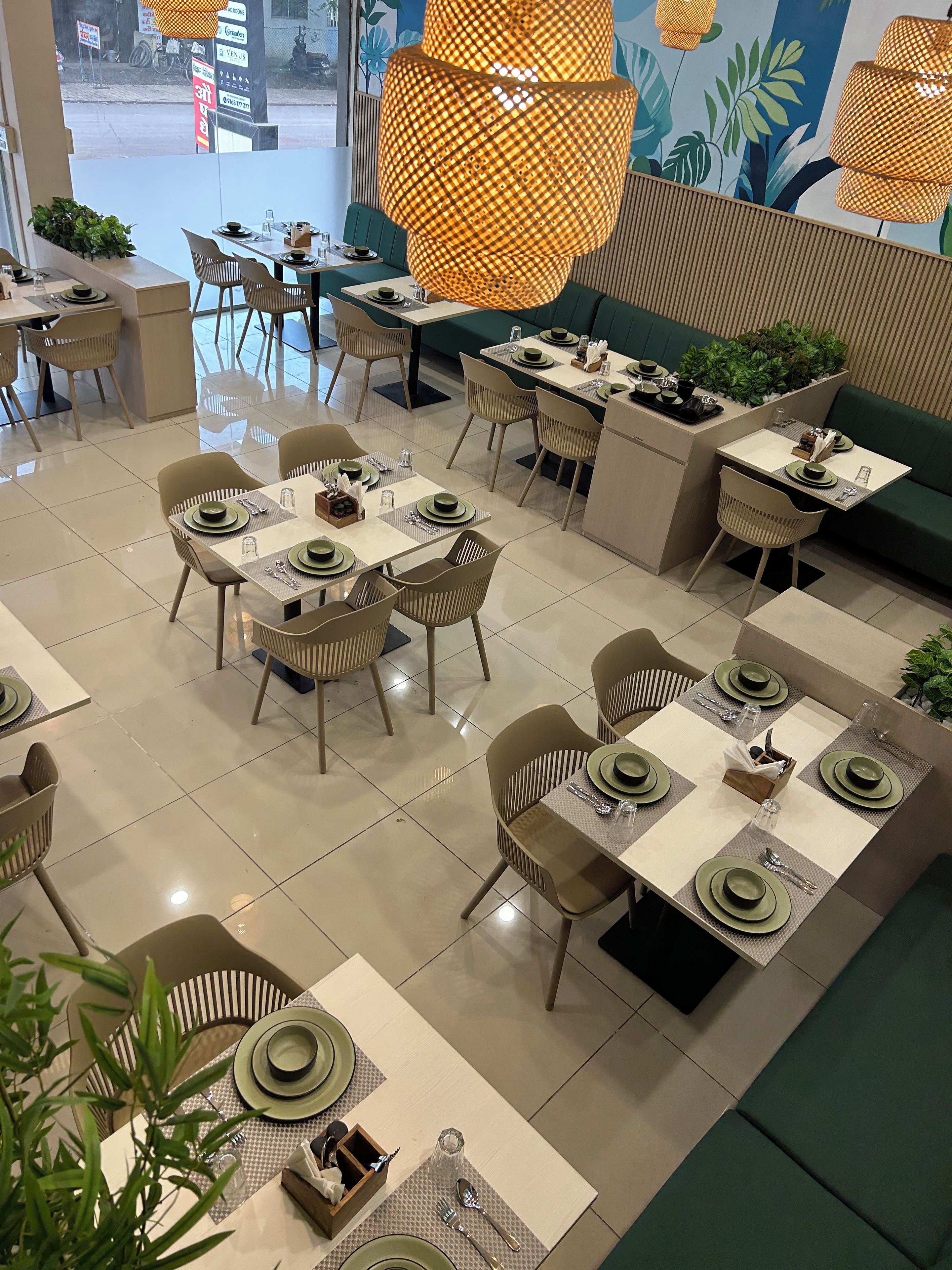 Un restaurante con varias mesas dispuestas para comer, con un diseño moderno en tonos verde y beige.