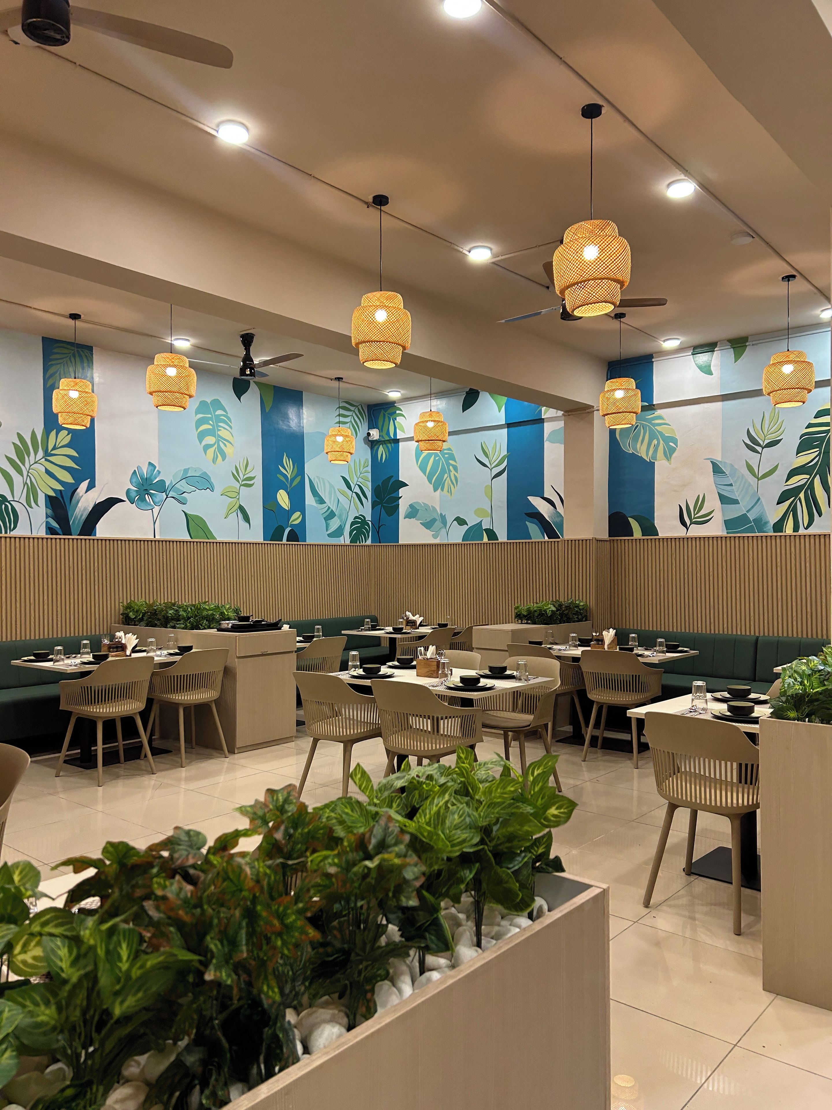 Un interior de restaurante moderno con varias mesas, sillas y lámparas colgantes de mimbre.
