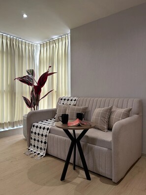 A modern living room with a sofa, a coffee table, and a potted plant. - The Solace Hotel (Nashik)