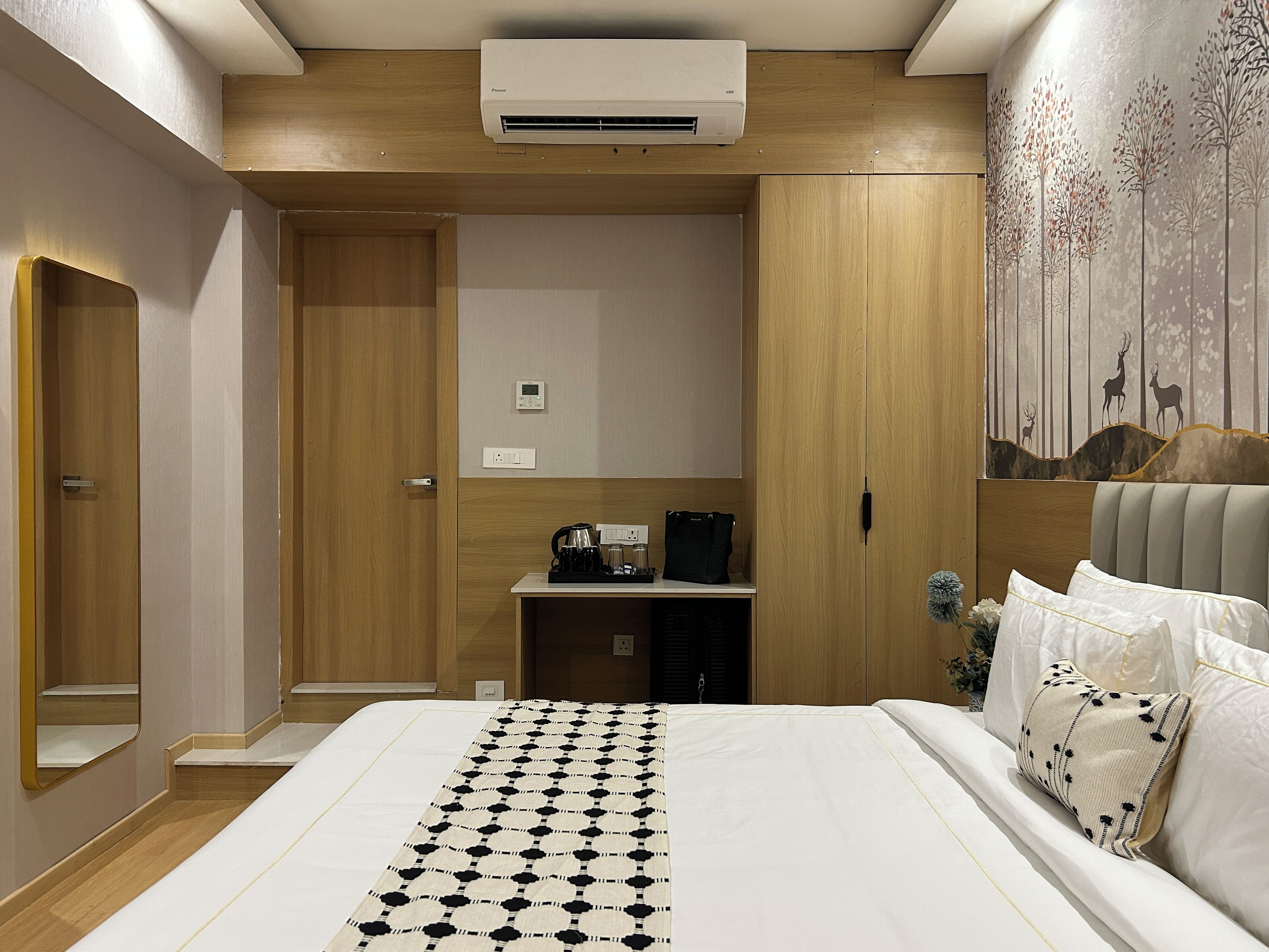 Un dormitorio moderno con una cama grande, una mesita de noche con tetera y un aire acondicionado instalado en la pared.