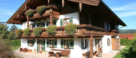 A traditional chalet with a balcony, wooden beams, and a garden.