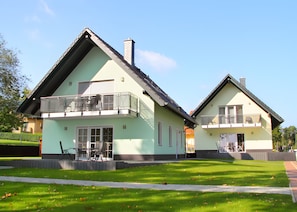 Two two-story houses with balconies, a lawn, and a clear sky. - Apartment 'U 2 EG Otter' with sea view, private terrace and Wi-Fi (Röbel/Müritz)