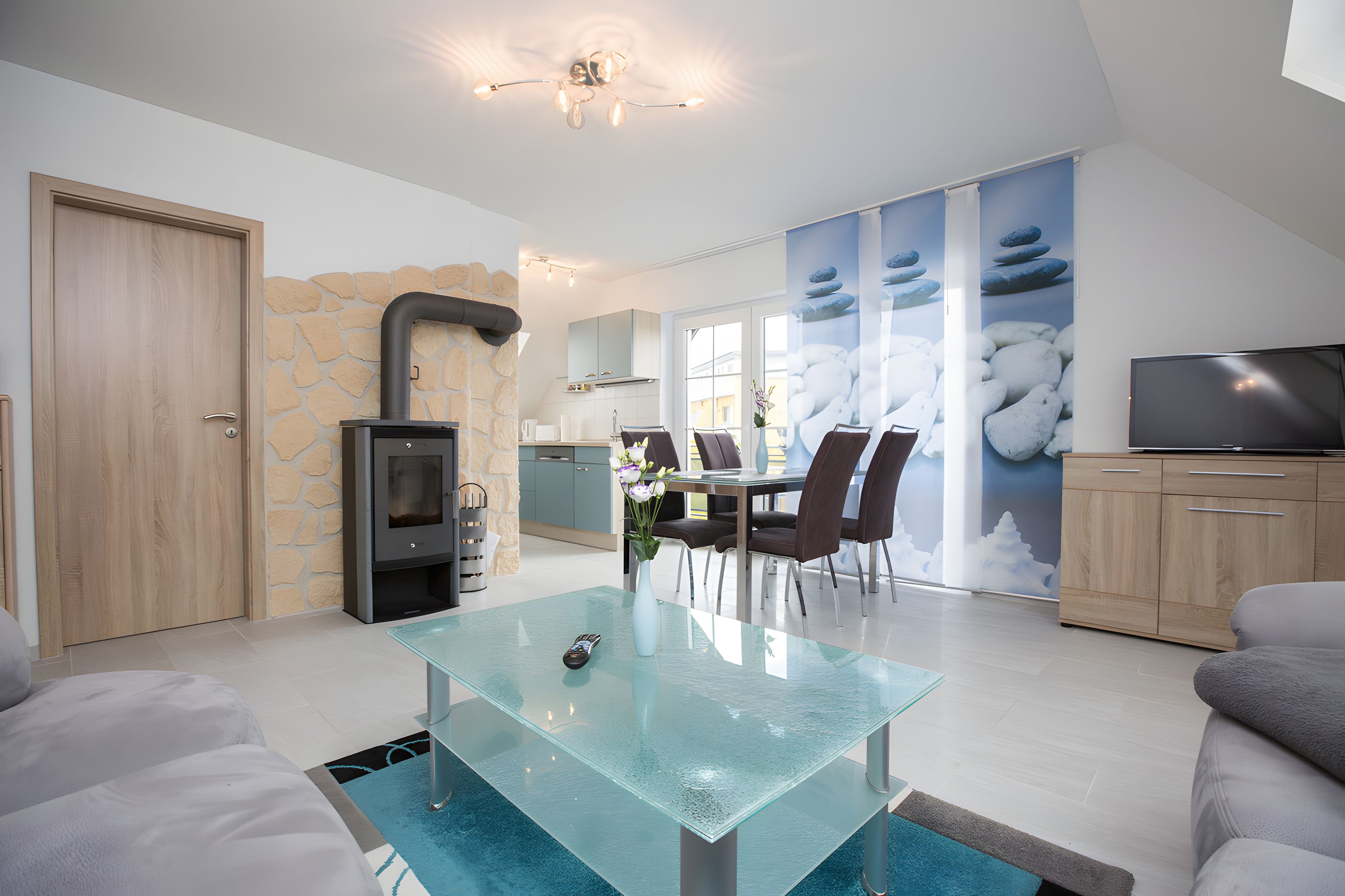 A modern living room with a glass coffee table, a fireplace, and a dining area with chairs and a table.