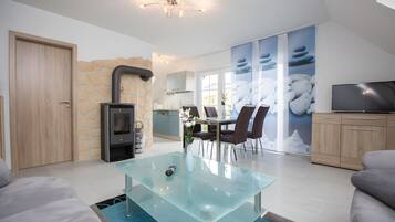 A modern living room with a glass coffee table, a fireplace, and a dining area with chairs and a table.