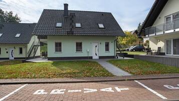 A residential building with a tiled roof, a front door, and a small garden area.