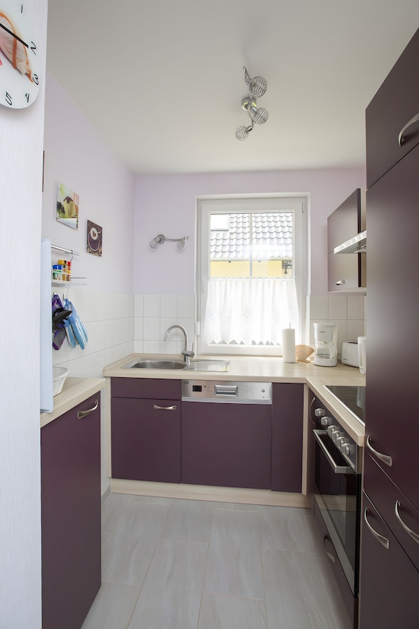 A compact kitchen with a sink, dishwasher, and oven. - Apartment 'U 2 EG Otter' with sea view, private terrace and Wi-Fi (Röbel/Müritz)