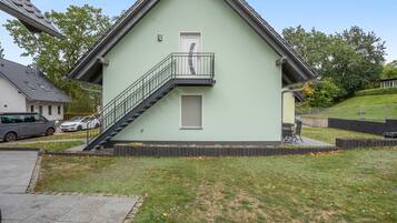 Ein zweistöckiges Gebäude mit Balkon, Treppe und kleinem Garten.