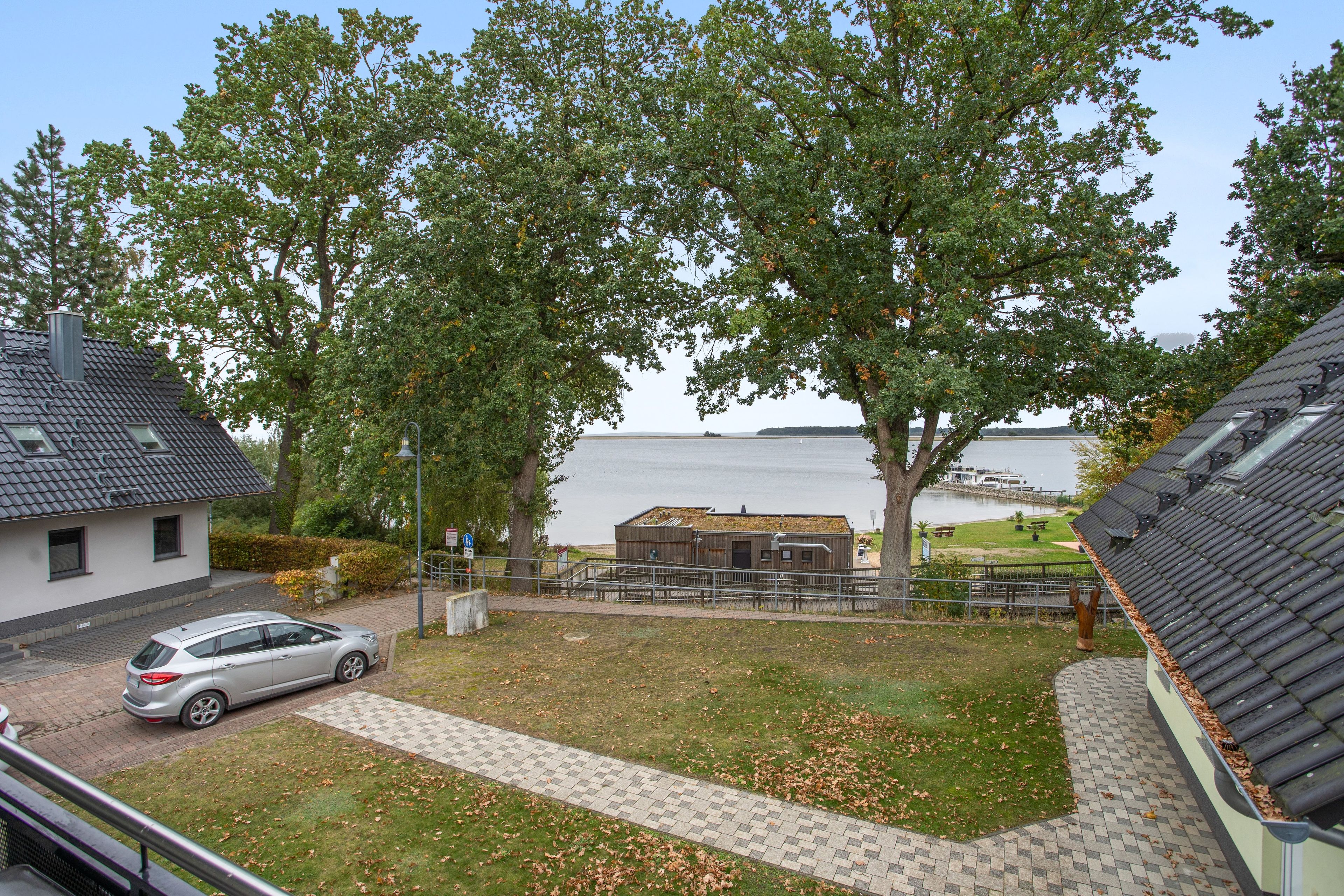 A residential area with a house, a car, a boat, and a lake.