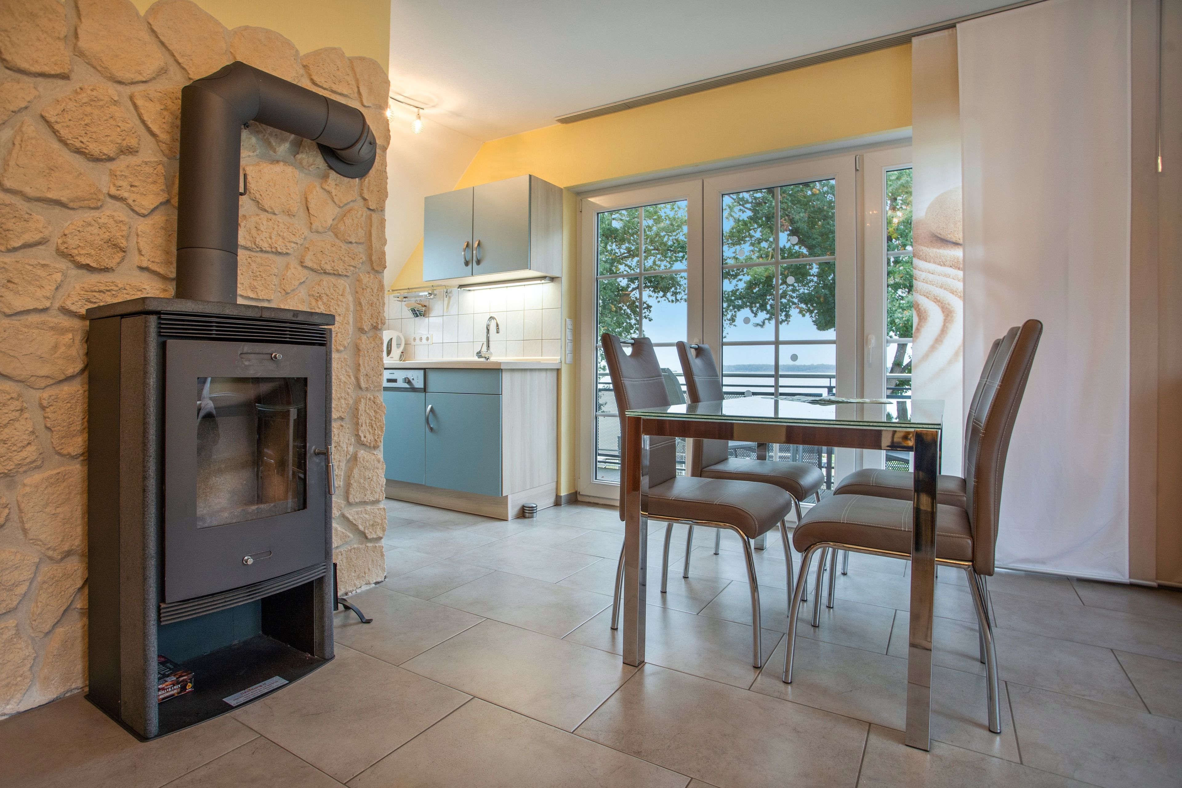 Een moderne keuken met een stenen muur, een inbouwfornuis en een eethoek met stoelen en een tafel.