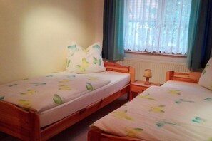 A room with two wooden beds, each with a matching pillow and a bedside table with a lamp. - Holiday apartment with 1 bedroom (Bonndorf)