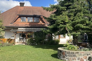 A house with a sloped roof, a front porch, and a stone retaining wall. - Holiday apartment with 1 bedroom (Bonndorf)