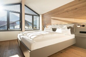 A modern bedroom with a large bed, wooden headboard, and a skylight. - Villa Alpjuwel-Himmelblick (Oberstdorf)